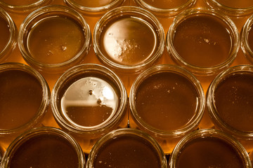 Golden yellow honey in glass jar on wooden board Closeup Copy space