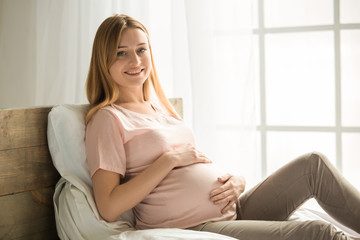 Young preganant woman expecting a baby relaxing on bed indoors