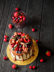 Berry birthday cake with chocolate on black wood desks