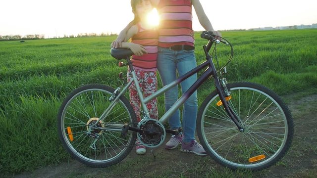 Woman with bicycle at sunset. Sports woman with a child on a bicycle. Sport family.