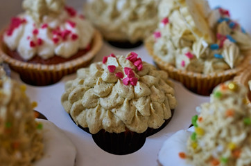 Cupcakes/Cupcakes for tea in the package. Beautiful variety of cupcakes with decorations in a box. Celebration, food, refreshment, chocolate and cream.
