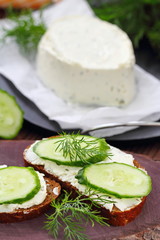 Sandwiches with soft cheese, cucumbers and greens