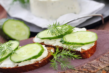 Sandwiches with soft cheese, cucumbers and greens