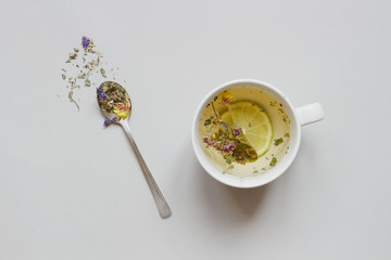 Tea time. Cup of hot herbal tea and dry tea on the gray background, top view