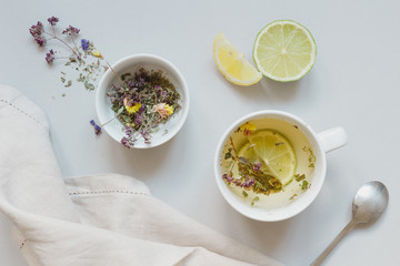 Tea time. Cup of hot herbal tea and dry tea on the gray background, top view