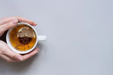 Papier Peint photo Lavable Theé L& 39 heure du thé. Mains tenant une tasse de thé noir chaud sur fond bleu, vue de dessus