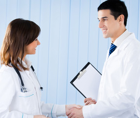 Fototapeta premium Two happy young medical people handshaking