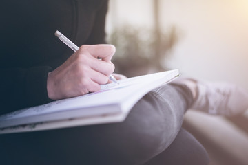 woman writing or scribbling on a notepad that is resting on her legs