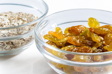 Oat flakes and raisins in a glass bowl isolated on white background. Closeup shot. Healthy food concept.