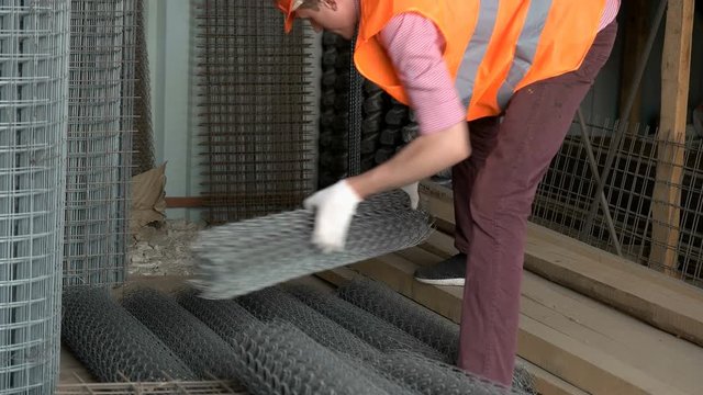 Worker puts iron mesh rolls in stock