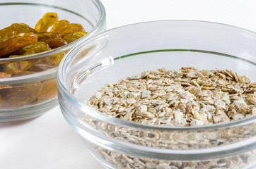 Oat flakes and raisins in a glass bowl isolated on white background. Closeup shot. Healthy food concept.