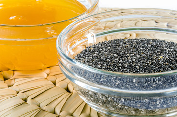 Chia seed and honey in a glass bowl on straw hot pad. Closeup shot. Healthy food concept.