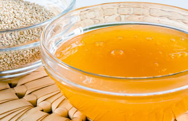 Quinoa and honey in a glass bowl on straw hot pad. Closeup shot. Healthy food concept.