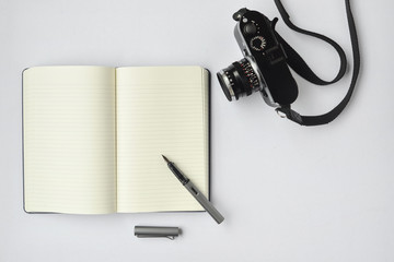 Notebook, pen, and camera, on white background