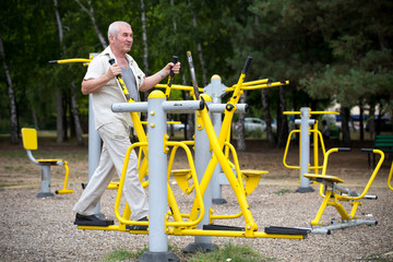 Old man making exercises on outdoor gym.
