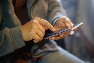 Man holding smart phone with blurred background.