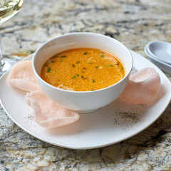 Creamy crab soup served with crab chips and glass of white wine on marble backround