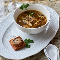 Asian cuisine. Mushroom soup with egg noodles served with toast, bread and white wine on marble background.