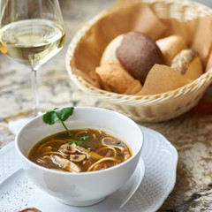 Asian cuisine. Mushroom soup with egg noodles served with toast, bread and white wine on marble background.