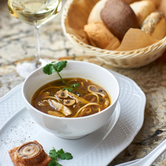 Asian cuisine. Mushroom soup with egg noodles served with toast, bread and white wine on marble background.