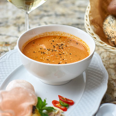 Peranakan cuisine. Singapore Laksa soup served with glass of white wine, bread, ceramic spoon, crab chips, slice of lemon and fresh vegetables on marble table