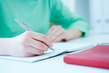 Female hands holding a silver pen closeup. Business woman making notes at office workplace. Business job offer, financial success, certified public accountant concept.