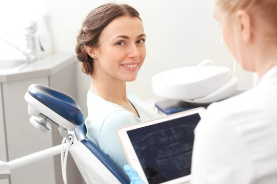 Dentist looking at X-ray image of young woman's teeth