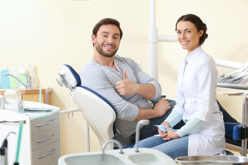 Obraz premium Happy young man and female dentist after treatment in clinic