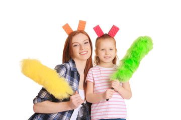 Little girl and her mother with cleaning supplies on white background