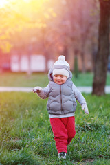 Toddler child in warm vest jacket outdoors. Baby boy at park during sunset.