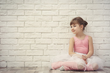 Obraz premium Little ballerina sitting on floor in dance studio