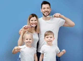 Wandcirkels Tandarts Young family brushing teeth on blue background  © Africa Studio
