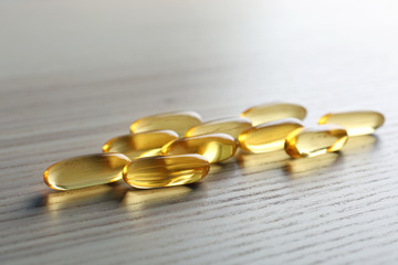 Fish oil capsules on wooden table