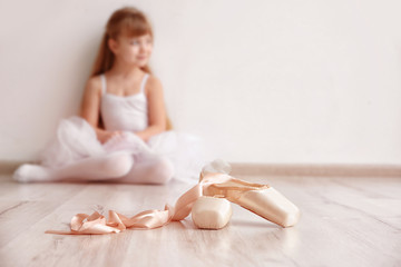 Ballet shoes and beautiful little ballerina in light dance studio