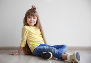 Little fashion girl sitting on floor in light room