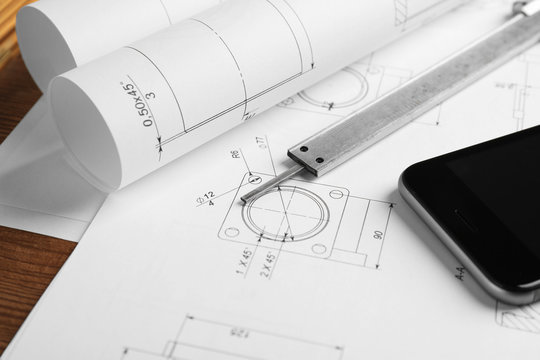 Calipers, phone and blueprints on engineer's workplace