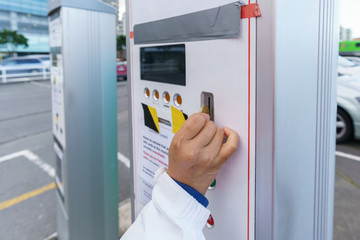  Woman's hand inserting coin in the car vending machine , paying for car park in the city