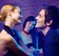 Young couple and woman looking at them at club