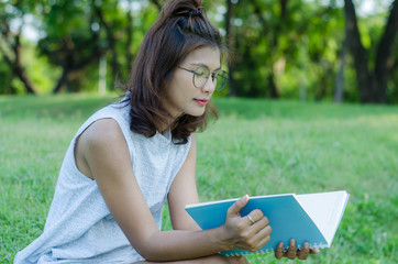 young beautiful girl reading a book on the grass green