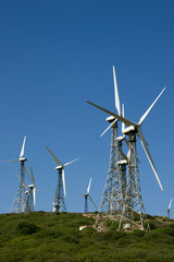 Fototapeta na wymiar Set of wind power mill towers against blue sky