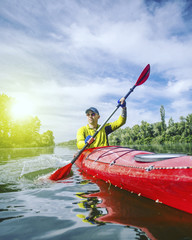 A man rafts on a kayak on the river in a sunny day.