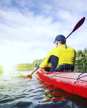 A man rafts on a kayak on the river in a sunny day.