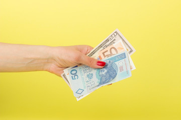 Fifty dollars, zloty and euro in the woman's hand, yellow background