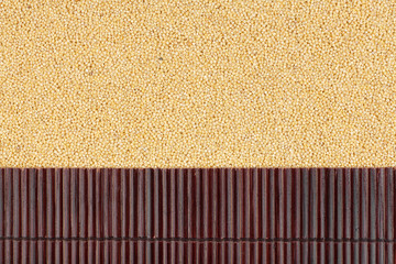 Fototapeta premium Beautiful bamboo mat on millet grains as agricultural background.