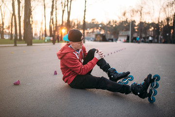 Roller skater sitting on asphalt in city park