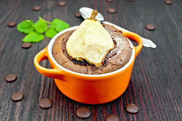 Cake with chocolate and pear in red bowl on dark board