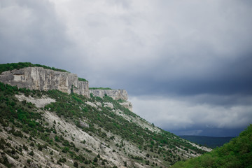 Fototapeta na wymiar wildlife is a beautiful rocky mountain with caves and cliffs with green trees rain clouds