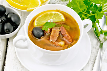 Solyanka with lemon in white bowl on board