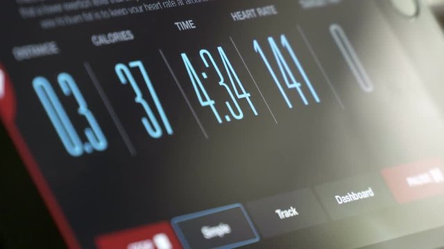 Fitness App displaying workout data on tablet screen time-lapse. Digital tablet linked with fitness machine displaying distance, burning calories, time and heart rate.