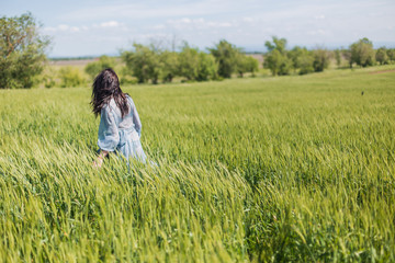 Fototapeta na wymiar hands, ears green, field, meadow, planting, summer, girl coming in a blue dress, nature, beautiful, trees, forest, clouds, horizontal